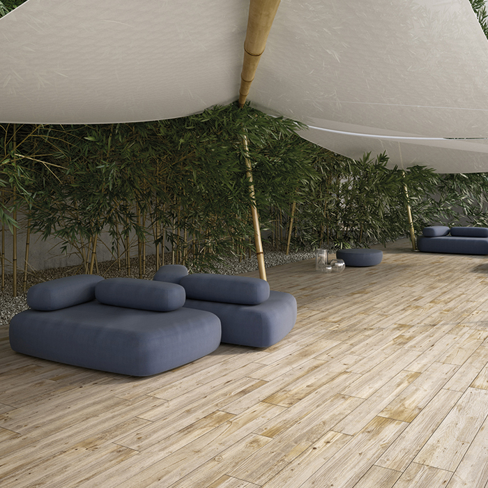 Ein Raum mit Holzoptikfliesen auf dem Boden und einem braunen Lederstuhl mit kleinem Beistelltisch im Hintergrund